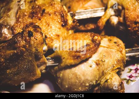 Hähnchenschenkel an den Spiessen in Nahaufnahme. Gebratenes Hähnchen Stockfoto