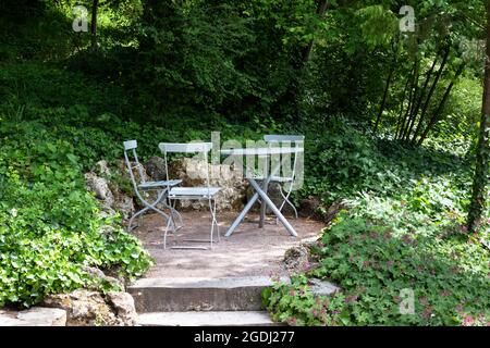 Eine gemütliche Sitzecke im Garten mit Klappstühlen und einem Tisch im Schatten der Bäume. Stockfoto