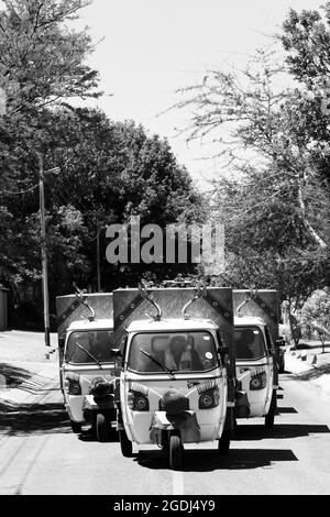 JOHANNESBURG, SÜDAFRIKA - 06. Jan 2021: Eine vertikale Aufnahme von kleinen TukTuk-Lebensmittelläden mit Heimzustellfahrzeugen, die durch Vororte fahren Stockfoto