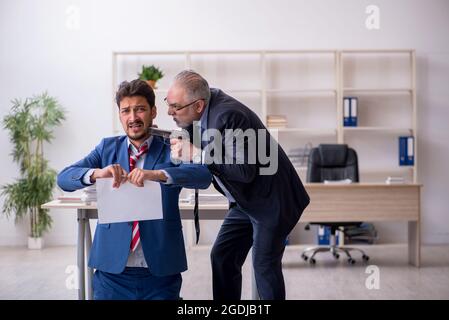 Alter Chef und junger Mitarbeiter im Mobbing-Konzept Stockfoto