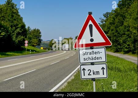 schild 'Vorsicht 2 km Straßenschaden' am Straßenrand, Deutschland Stockfoto