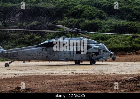 210803-N-MO469-1010 SANTA RITA, Guam (Aug 3, 2021) die dem HSC-25 zugewiesene Luftbesatzung landet eine MH-60S auf einem Prototyp-Landeplatz, der von Seabees gebaut wurde und dem Naval Mobile Construction Bataillon (NMCB) 11 det. Guam. Die Landeplatz wurde unter der Unterstützung von III MEF mit einem Biozement-Applikationssystem konstruiert, das von bioMASON mit Unterstützung der Defense Advanced Research Projects Agency entwickelt wurde. Das Biozement-Anwendungssystem wurde für den Einsatz in Vorwärtsoperationspositionen auf nativen, nicht entwickelten Oberflächen entwickelt, um den Boden zu stärken, die Erosionskontrolle zu fördern und die Staubentwicklung zu erhöhen Stockfoto