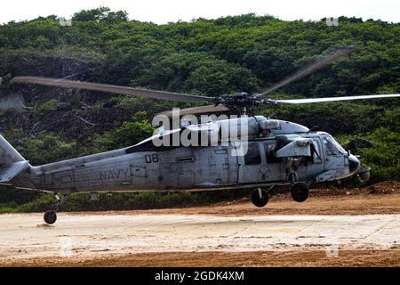 210803-N-MO469-1012 SANTA RITA, Guam (Aug 3, 2021) die dem HSC-25 zugewiesene Luftbesatzung landet eine MH-60S auf einem Prototyp-Landeplatz, der von Seabees gebaut wurde und dem Naval Mobile Construction Bataillon (NMCB) 11 det. Guam. Die Landeplatz wurde unter der Unterstützung von III MEF mit einem Biozement-Applikationssystem konstruiert, das von bioMASON mit Unterstützung der Defense Advanced Research Projects Agency entwickelt wurde. Das Biozement-Anwendungssystem wurde für den Einsatz in Vorwärtsoperationspositionen auf nativen, nicht entwickelten Oberflächen entwickelt, um den Boden zu stärken, die Erosionskontrolle zu fördern und die Staubentwicklung zu erhöhen Stockfoto