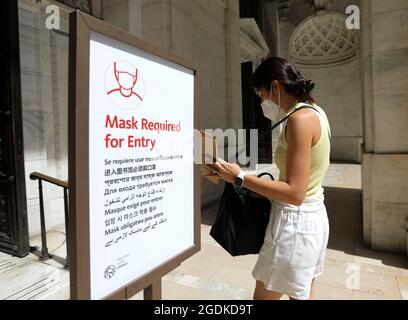 New York, USA. August 2021. Eine Frau geht an einem Zeichen der Gesichtsmaske vorbei, bevor sie die New York Public Library in New York City, USA, am 2. August 2021, betreten. Quelle: Wang Ying/Xinhua/Alamy Live News Stockfoto