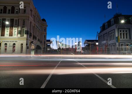 Städtische Straße bei Nacht bei langer Belichtung mit horizontalen Lichtstreifen von vorbeifahrenden Fahrzeugen, Wellington Neuseeland. Stockfoto