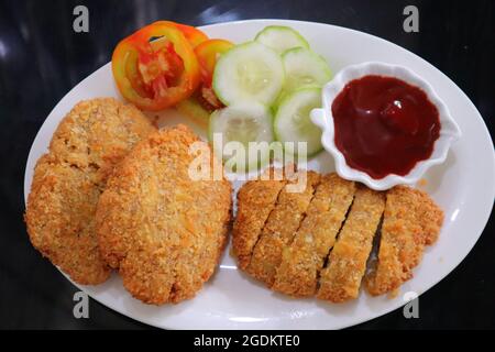 Fisch mit Gemüse und roter Sauce auf weißem Teller Stockfoto