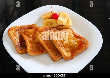 Honigverglaster französischer Toast mit Früchten auf weißem Teller Stockfoto