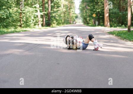 Baby in schützender Sportkleidung. Kleines Mädchen bekam eine Knieverletzung beim Rollschuhlaufen im Park. Stockfoto