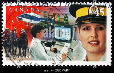 KANADA - UM 1998: Eine in Kanada gedruckte Marke zeigt weibliche mountie, Hubschrauber und Stadtbild, Royal Canadian Mounted Police, 125. Jahrestag, circa Stockfoto