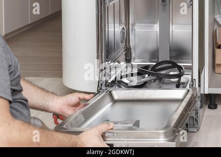 Der Master entfernte die Gummidichtungen und demontierte den eingebauten Geschirrspüler zur Reparatur Stockfoto