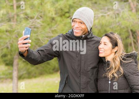 Fitness-Paar in warmen Kleidern nimmt ein Selfie im Park Stockfoto