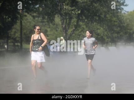 New York, USA. August 2021. Menschen gehen im Nebelgarten in der Nähe von Unisphere im Flushing Meadows Corona Park in New York, USA, 13. August 2021. Eine Hitzewelle traf vor kurzem New York City. Quelle: Wang Ying/Xinhua/Alamy Live News Stockfoto