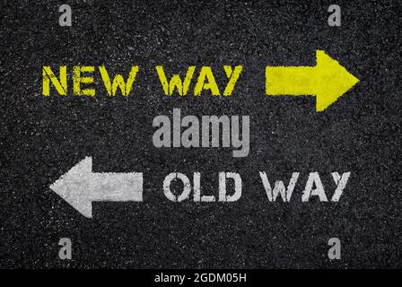 „New Way“- und „Old Way“-Schilder/-Texte mit Pfeilen, die auf dunkle, nasse schwarze Asphaltstraße in entgegengesetzte Richtungen zeigen, Draufsicht. Strukturierter Hintergrund. Stockfoto