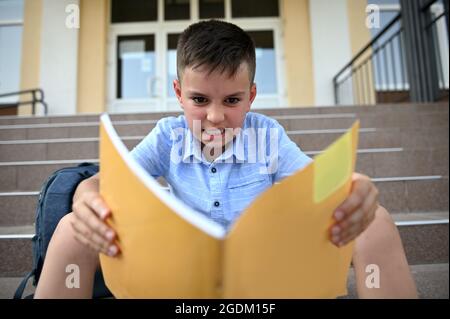 Unglücklich, besorgt, frustriert und wütend Schüler, Schüler, fühlt negative Emotionen beim Lesen und Hausaufgaben zu tun. Lernschwierigkeiten Konzept. Zurück Stockfoto