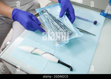 Nicht erkennbarer Zahnarzt beim Auspacken sterilisierter Instrumente Stockfoto