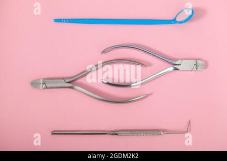 Draufsicht Nahaufnahme von Zangen und Zahnärzten Instrumenten auf rosa Hintergrund Stockfoto