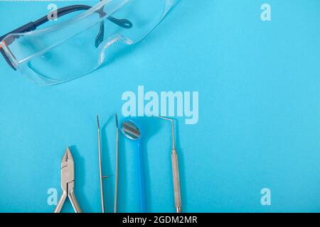 Nahaufnahme von oben Aufnahme von Schutzbrillen und zahnärztlichen Instrumenten auf blauem Hintergrund Stockfoto