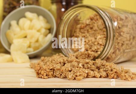 Bio-Honig mit Müsli, getrockneter Ananas und Äpfeln in rustikaler Küche Stockfoto