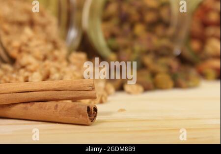 Zimtstangen mit Granola-Kellen und Nüssen im Hintergrund Stockfoto
