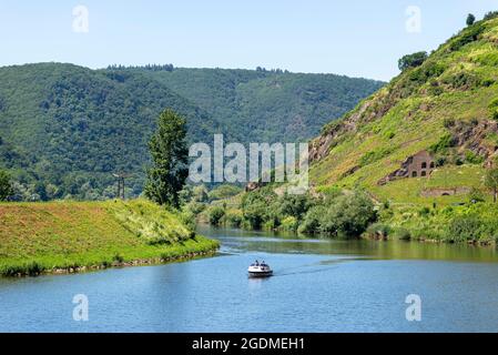 Zwei Männer segeln mit einem Motorboot auf einem ruhigen Fluss zwischen den mit Wald bedeckten Hügeln. Stockfoto