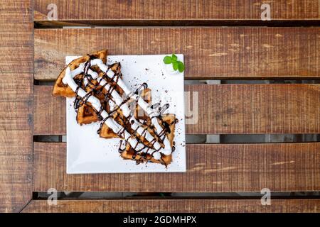 Waffeln In Nahaufnahme. Belgische Waffeln mit Schlagsahne und Schokoladensirup, serviert und verzehrt. Selektiver Fokus Stockfoto