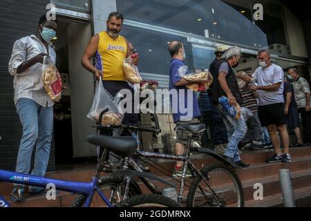 Beirut, Libanon. August 2021. Die Menschen gehen aus einer lokalen Bäckerei, nachdem sie sich inmitten der schweren Kraftstoffknappheit und Stromausfälle, die das Land derzeit lähmen, inmitten einer der schlimmsten Wirtschaftskrise der Welt in letzter Zeit, Brotpakete geholt haben. Quelle: Marwan Naamani/dpa/Alamy Live News Stockfoto