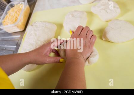 Weibliche Hände kneten einen Hefeteig, so dass sie sich darauf vorbereiten, ein Pizzabrot zu backen. Stockfoto