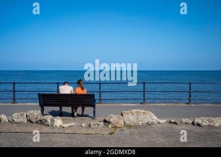 Ein Paar auf einer Bank am Meer, Filey, North Yorkshire, Großbritannien Stockfoto