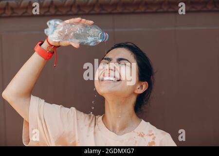 Gestresste Frau, die unter einem Hitzschlag und erfrischendem Ausgießen mit kaltem Wasser leidet. Wetter abnorme Wärme Konzept Stockfoto