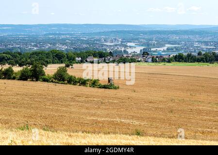 Das Stoppelfeld im Sommer im Hintergrund, der Fluss zwischen den Gebäuden und der Brücke, Luftaufnahme. Stockfoto