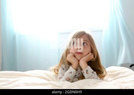 Junges Mädchen von sieben Tagträumen in ihrem Schlafzimmer Stockfoto