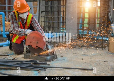 Der Arbeiter schneidet Stahl mit einer Trennscheibe der Schneidmaschine ab, bis beim Schneiden von Stahl Funken entstehen. Stockfoto