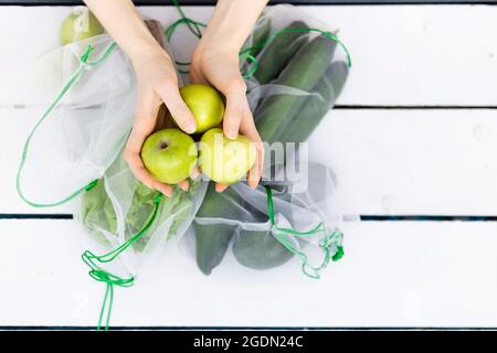 Von oben drei grüne Äpfel in den Händen der jungen Frau Stockfoto