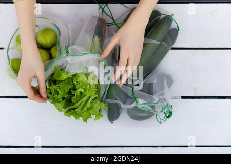 Draufsicht auf Salat im wiederverwendbaren Beutel in den Händen der jungen Frau Stockfoto