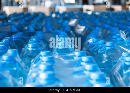 Blaue fünf-Liter-Wasserflaschen aus Kunststoff, die im Fertigwarenlager verpackt sind. Lebensmittelproduktion Stockfoto