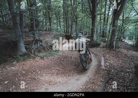 Rückaufnahme einer weiblichen Mountainbikerin auf dem Flow Trail, die eine Kurve nimmt Stockfoto