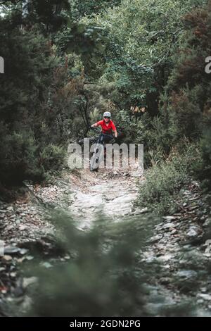 Mittellange Nahaufnahme einer weiblichen Mountainbikerin auf einem felsigen Trail Stockfoto