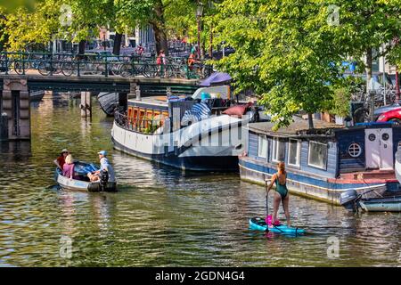 Niederlande, Amsterdam, Brouwersgracht. Unesco-Weltkulturerbe. Hausboote, Hausboote, kleines Boot und Frau auf dem Boot. Sommer. Stockfoto