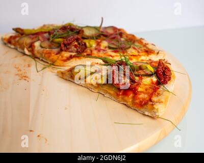 Vegetarische Pizza letzte zwei Stücke, auf einem Holztisch, heller Hintergrund Stockfoto