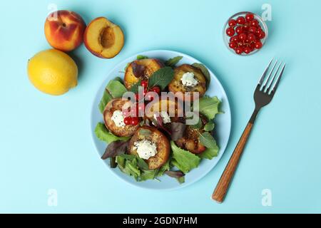 Salatplatte mit gegrilltem Pfirsich auf blauem Hintergrund Stockfoto