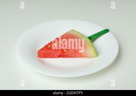 Eisstock mit Wassermelonenscheibe auf Teller auf weißem Hintergrund Stockfoto