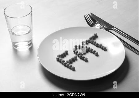 Anorexie. FETT mit Erbsen auf einen Teller spelzen. Stockfoto