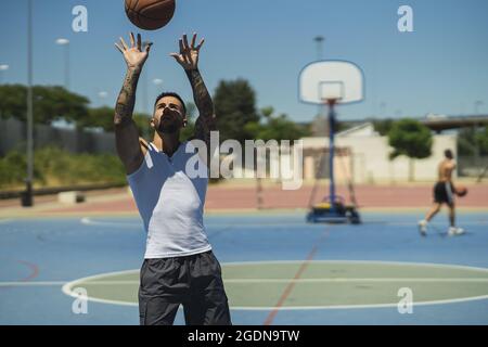 Junger muskulöser Mann spielt Basketball auf dem Spielplatz Stockfoto