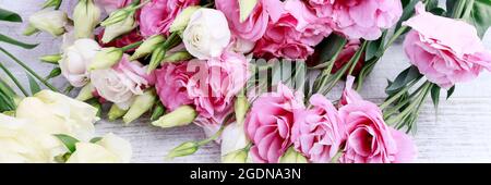 Rosa und gelbe Blüten auf weißem Holztisch. Stockfoto