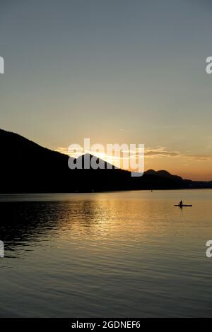 Reste des Tages am See. Die Sonne geht hinter den silhouettierten Bergen in Österreich unter. Hochformat, Fuschl See, Fuschl am See Stockfoto