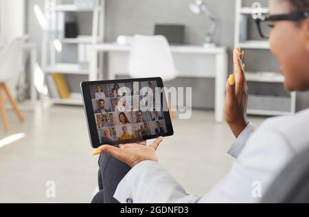 Frau, die mit ihrem Geschäftsteam per Videoanruf auf ihrem Tablet-Computer kommuniziert Stockfoto