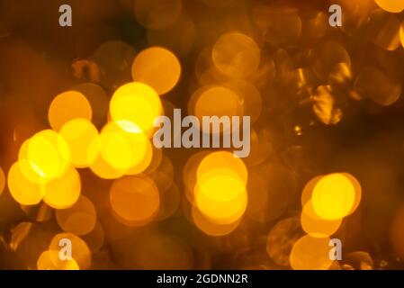 Verschwommenes weihnachtslicht abstrakter Hintergrund vor dunkler Kulisse. Kreisförmige Reflexionen von Weihnachtslichtern Stockfoto