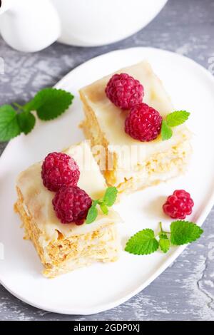 Stücke von Napoleon Kuchen mit Himbeeren und Zitronenmelisse Blätter auf einem hellen Hintergrund verziert. Stockfoto
