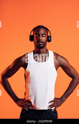 Afroamerikanischer Athlet, der über kabellose Kopfhörer Musik hört. Mann in Sportleinen beim Fitnesstraining entspannen. Stockfoto
