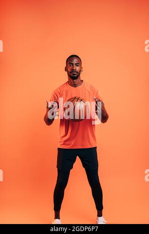 Der junge Sportler wirft den Ball vor ihm im Studio in die Luft Stockfoto